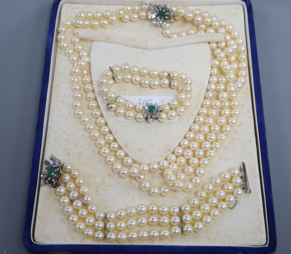 A triple strand cultured pearl necklace and matching bracelet with white metal, emerald and diamond set clasps & 1 other bracelet.
